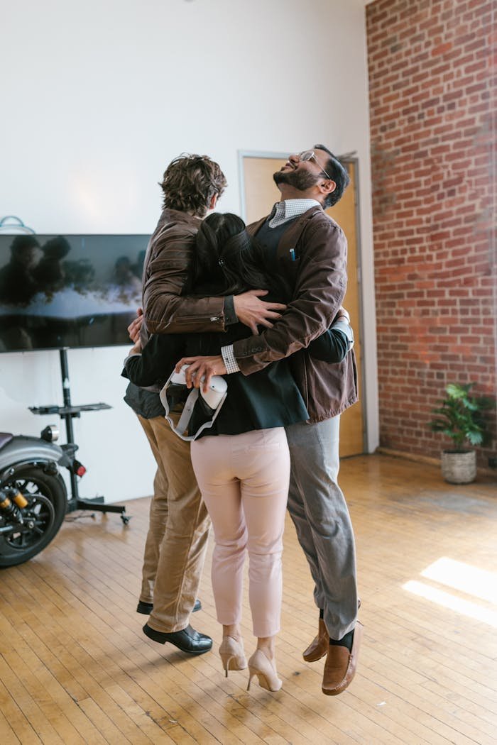 Group of business professionals in a cheerful embrace, celebrating success indoors.